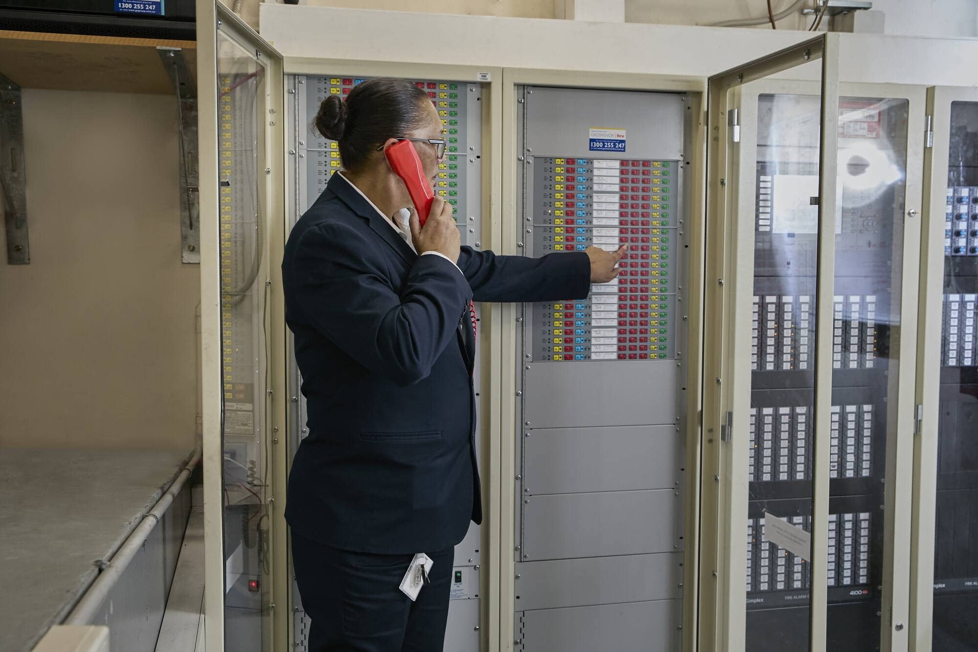 EGroup officer using phone beside fire and safety control panel